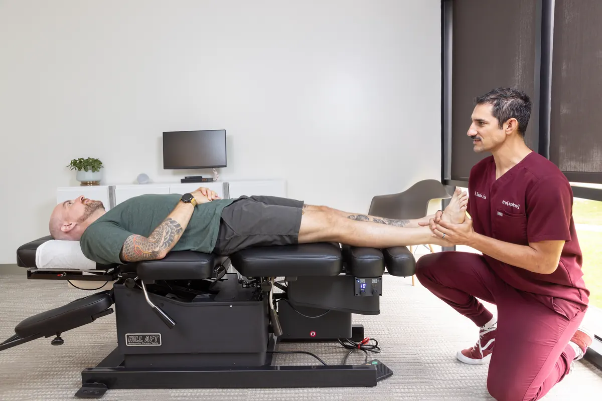 Dr. Brandon Fein assessing and adjusting a patient's ankle at TruSpine San Francisco