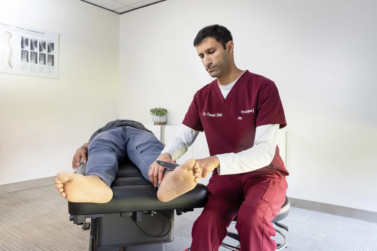 Dr. Supreet Shah using a handheld adjusting instrument for a gentle chiropractic adjustment