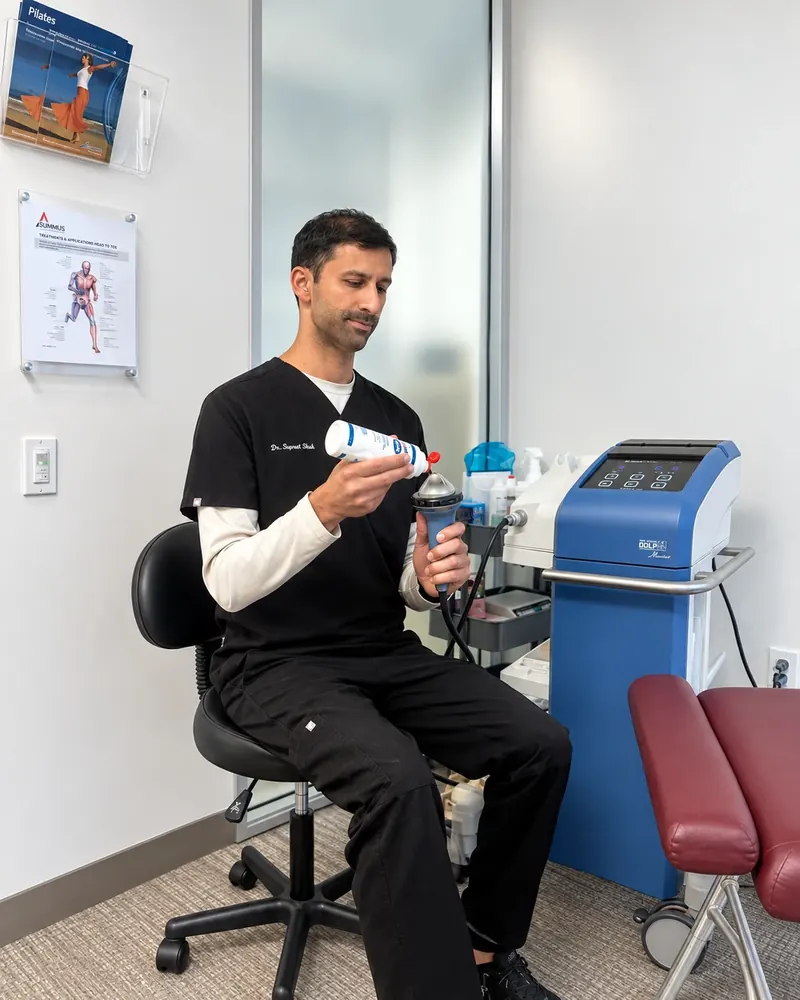 Applying coupling gel to the shockwave therapy handpiece before a treatment at Truspine San Francisco