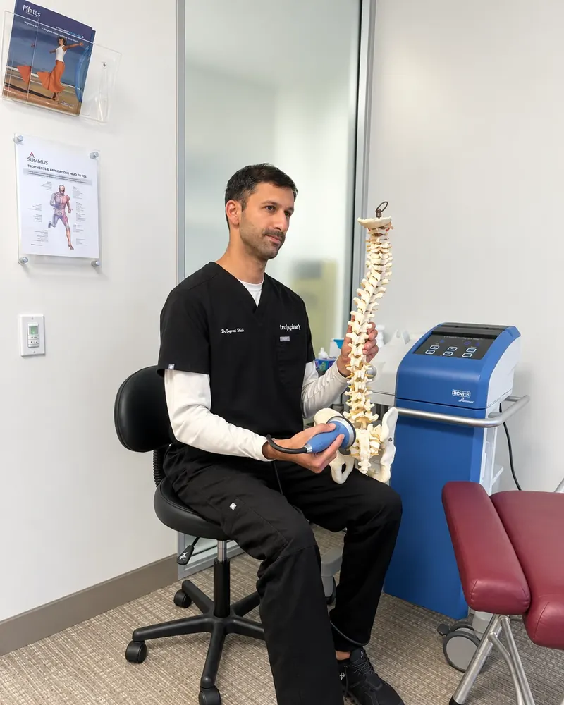 Dr. Supreet Shah using a spine model to explain how focused shockwave therapy works at Truspine San Francisco